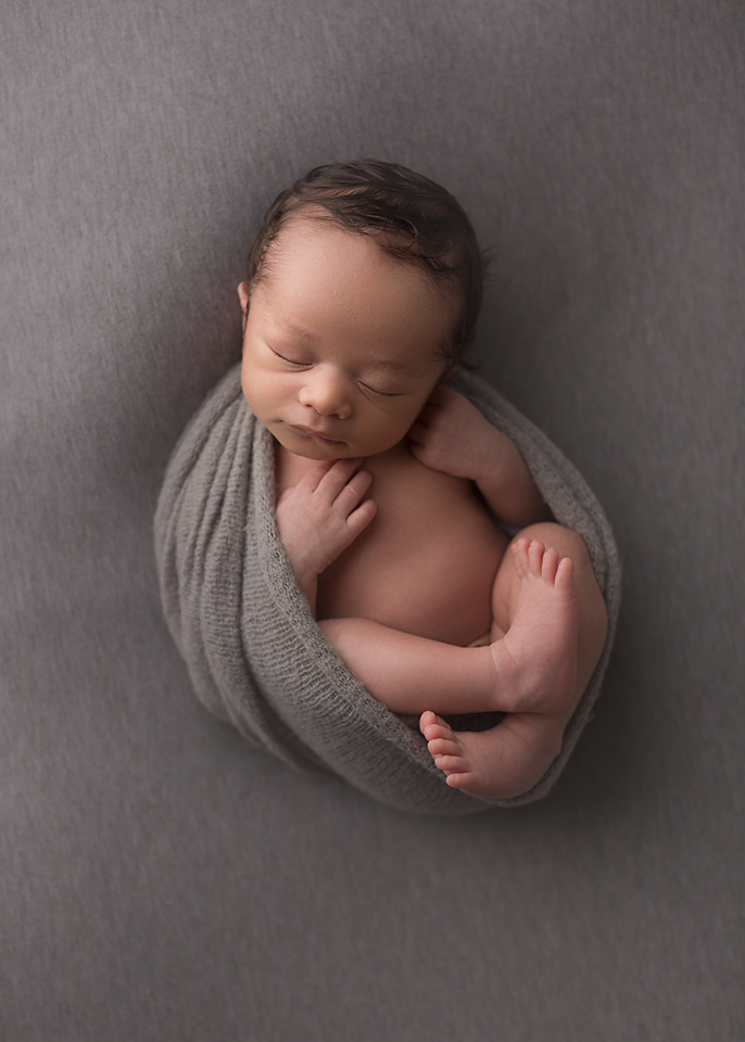 newborn baby photograph, newborn photography, baby in grey wrap, baby on back asleep. newborn photographed in southern Maryland